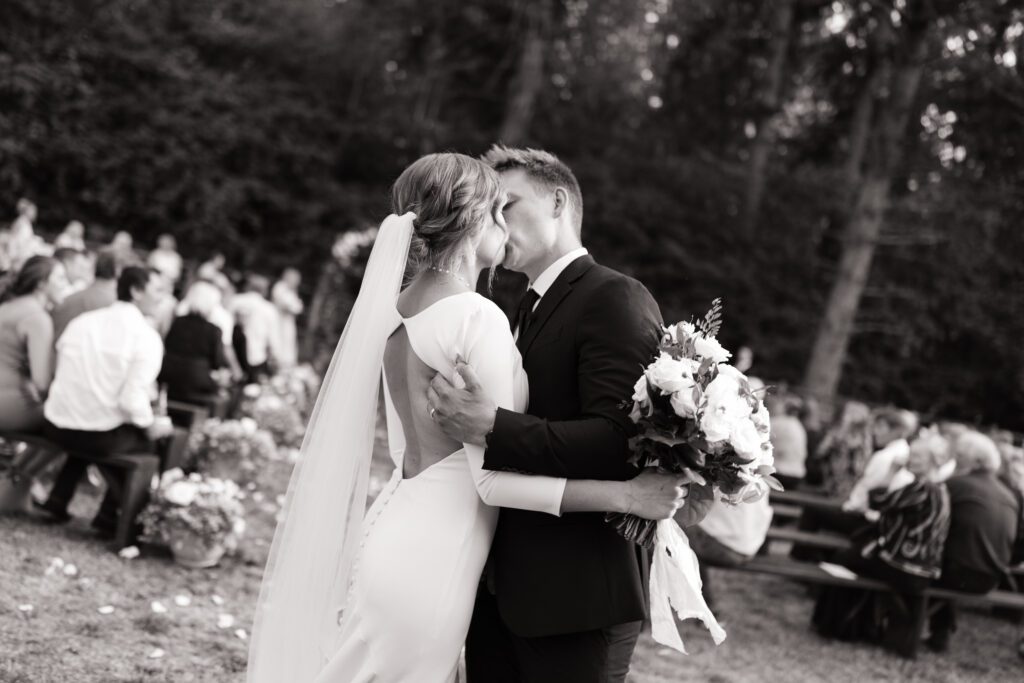 Newlyweds share a kiss after walking down the aisle, surrounded by the joy and celebration of their wedding ceremony in Vancouver, WA