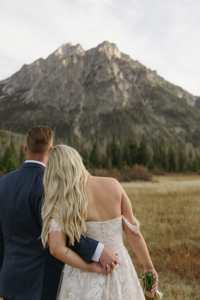 Bride and groom standing together, gazing at the majestic Sawtooth Mountain range in Idaho