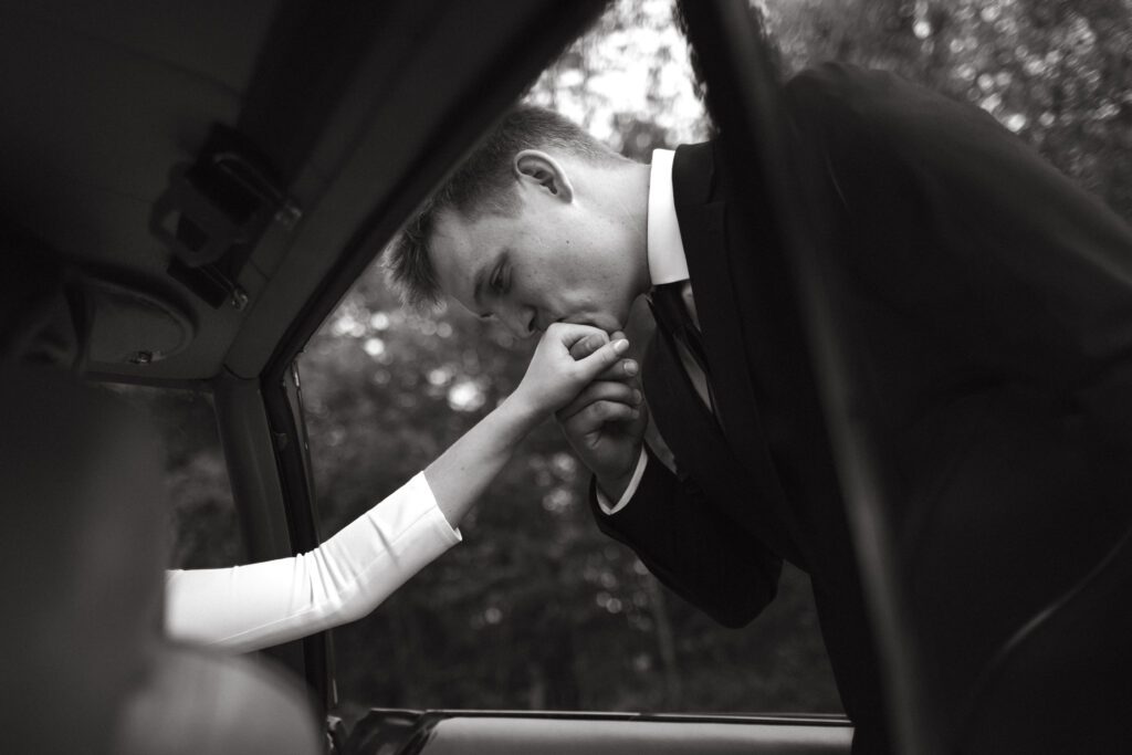 The bride and groom share a loving gaze while leaning against Creighton's classic car, showcasing their deep connection and shared passions