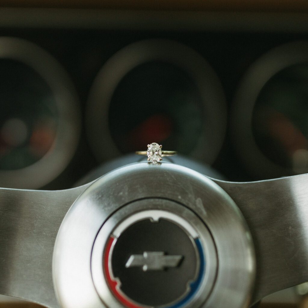 A close-up of the wedding rings resting on the steering wheel of Creighton's classic car, symbolizing their union and shared love