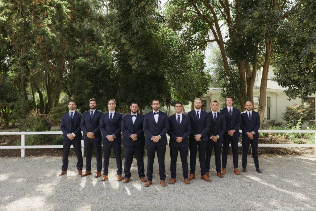 Groom and groomsmen in suits, posing for a photo with cheerful expressions