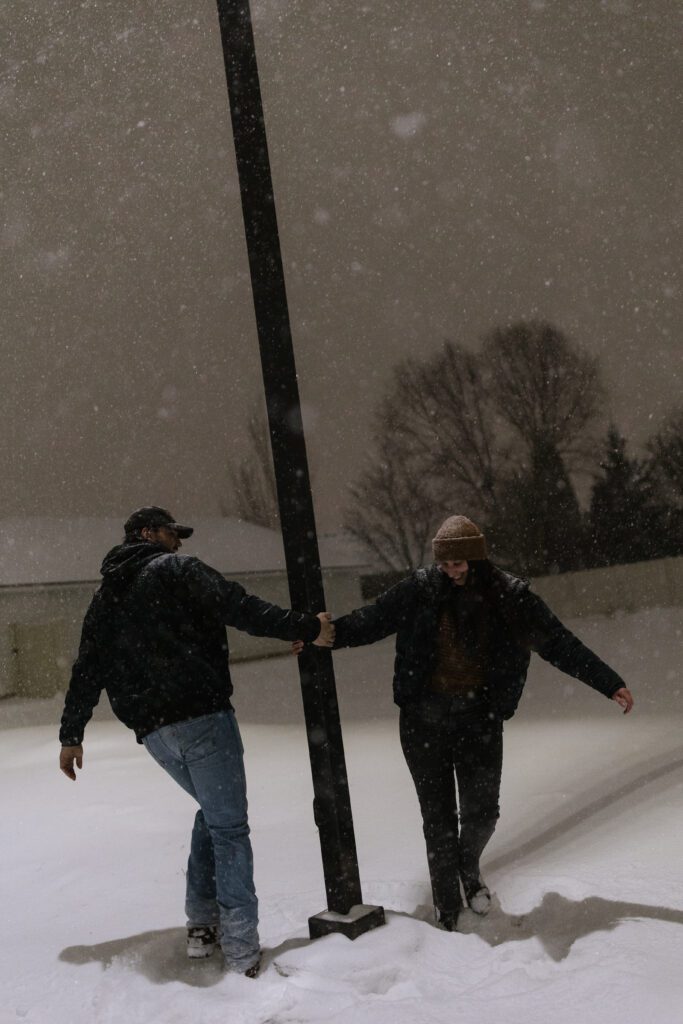 couple dances and plays in snow for engagement photos in boise.