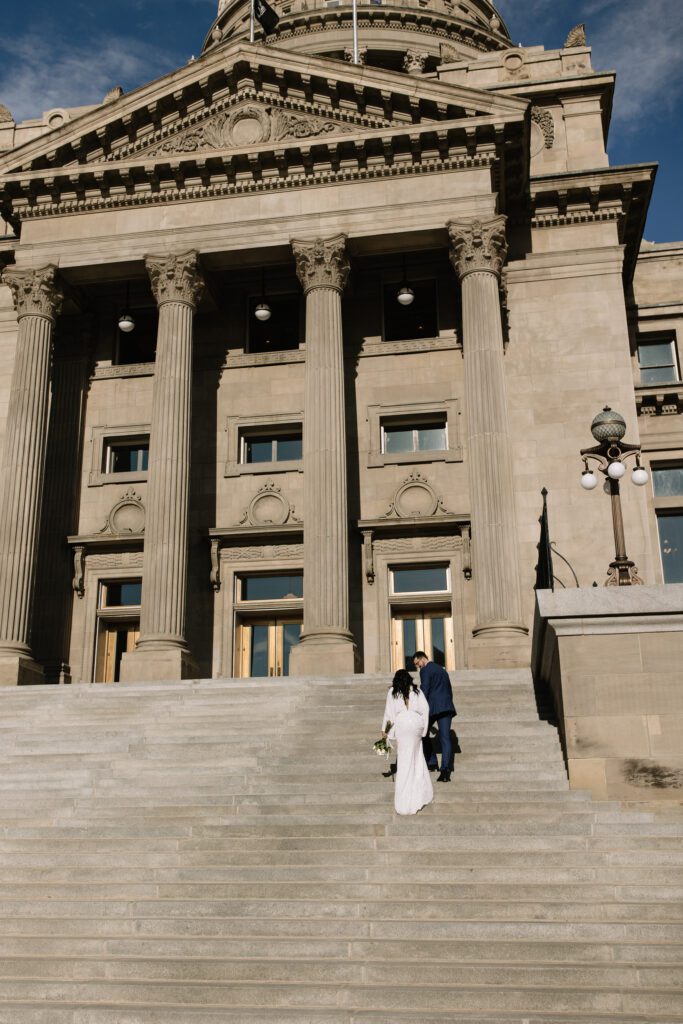 Couple walk hand in hand up the front steps of Boise's Capitol building for their Private Idaho Courthouse Elopement