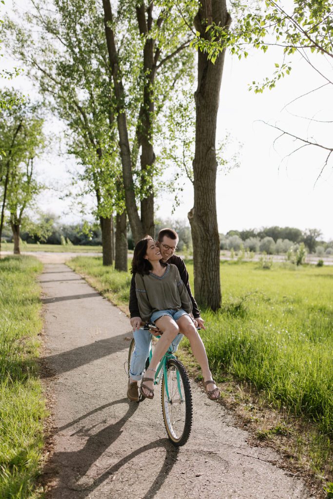 Couple riding a vintage bike together through Boise, smiling and laughing as they share the seat