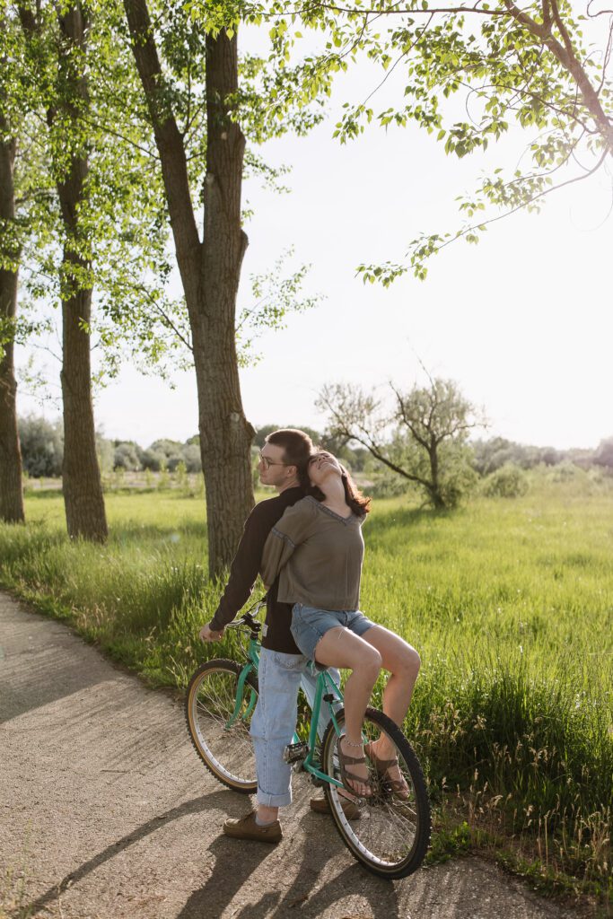 Boise couple pedaling down a quiet path on their vintage bike, holding hands and soaking in golden hour light.
