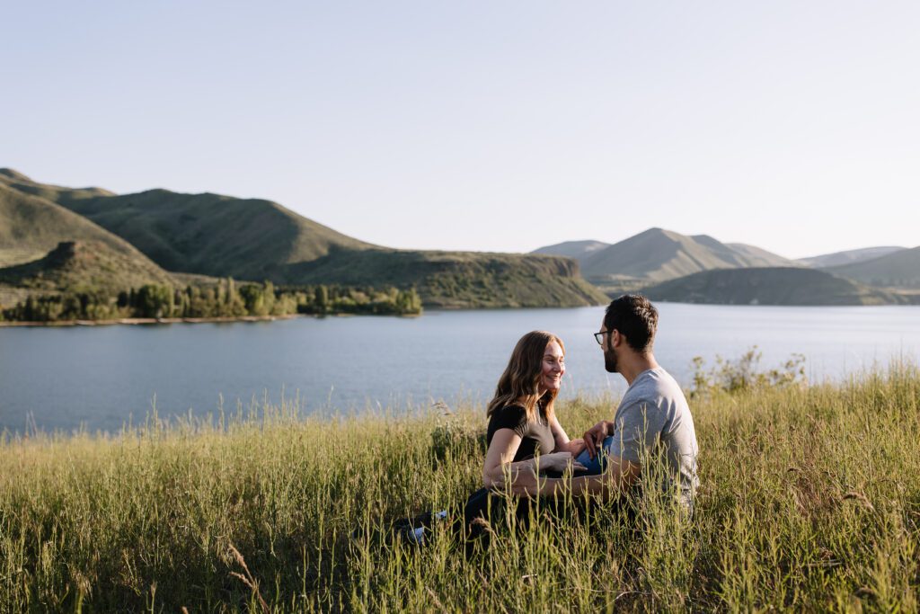 Boise couple sat with a view of Lucky Peak Lake for their golden hour engagement session