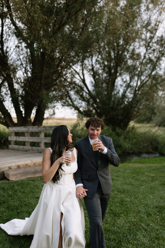 Bride laughing while holding hands with her partner during sunset portraits.