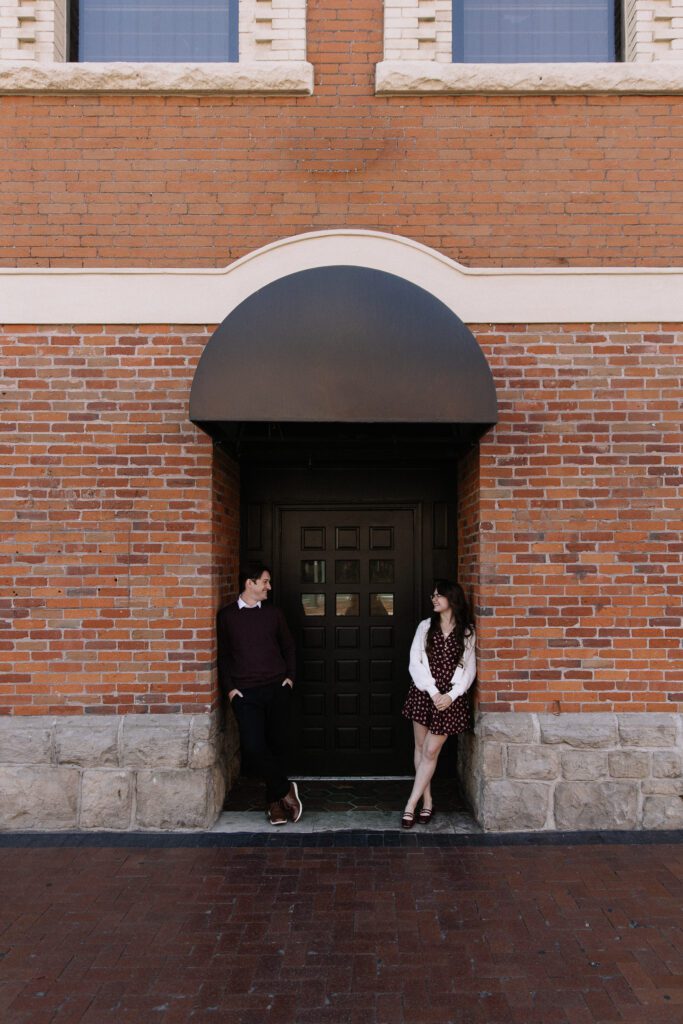 Couple pose together outside Pengilly Saloon for engagement photos in Boise.