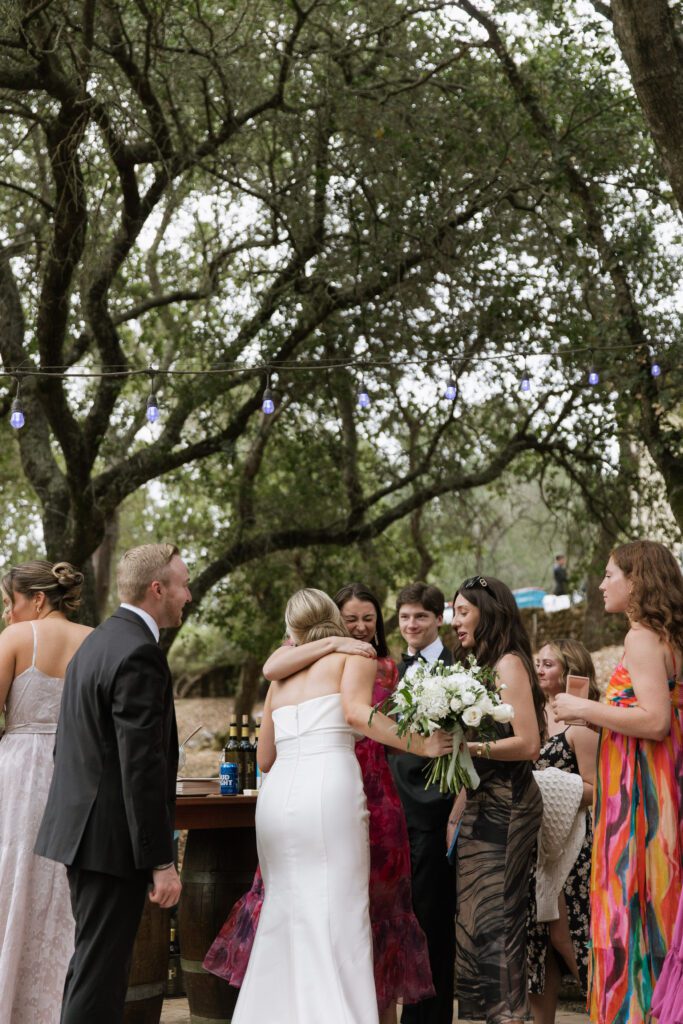 Bride greets guests during cocktail hour at outdoor wedding reception.