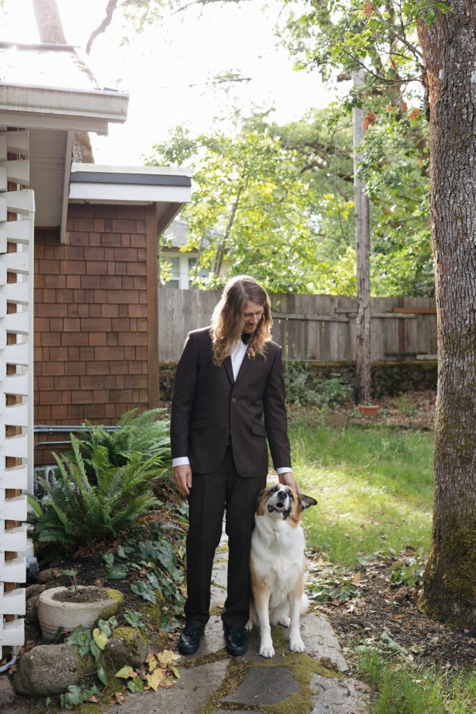 Groom poses with dog during intimate Oregon elopement.