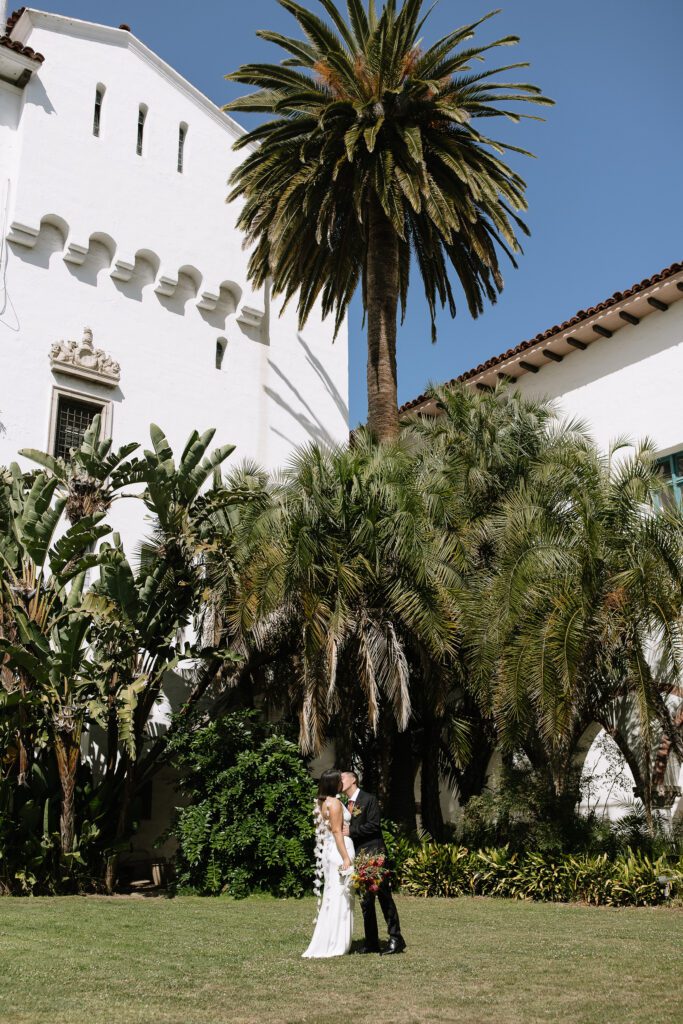 Couple embracing beneath the palm trees of the Santa Barbara Courthouse.