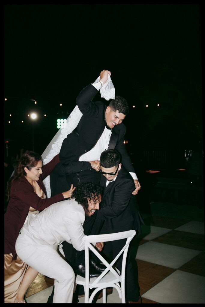 Groom dancing with groomsmen on dance floor.